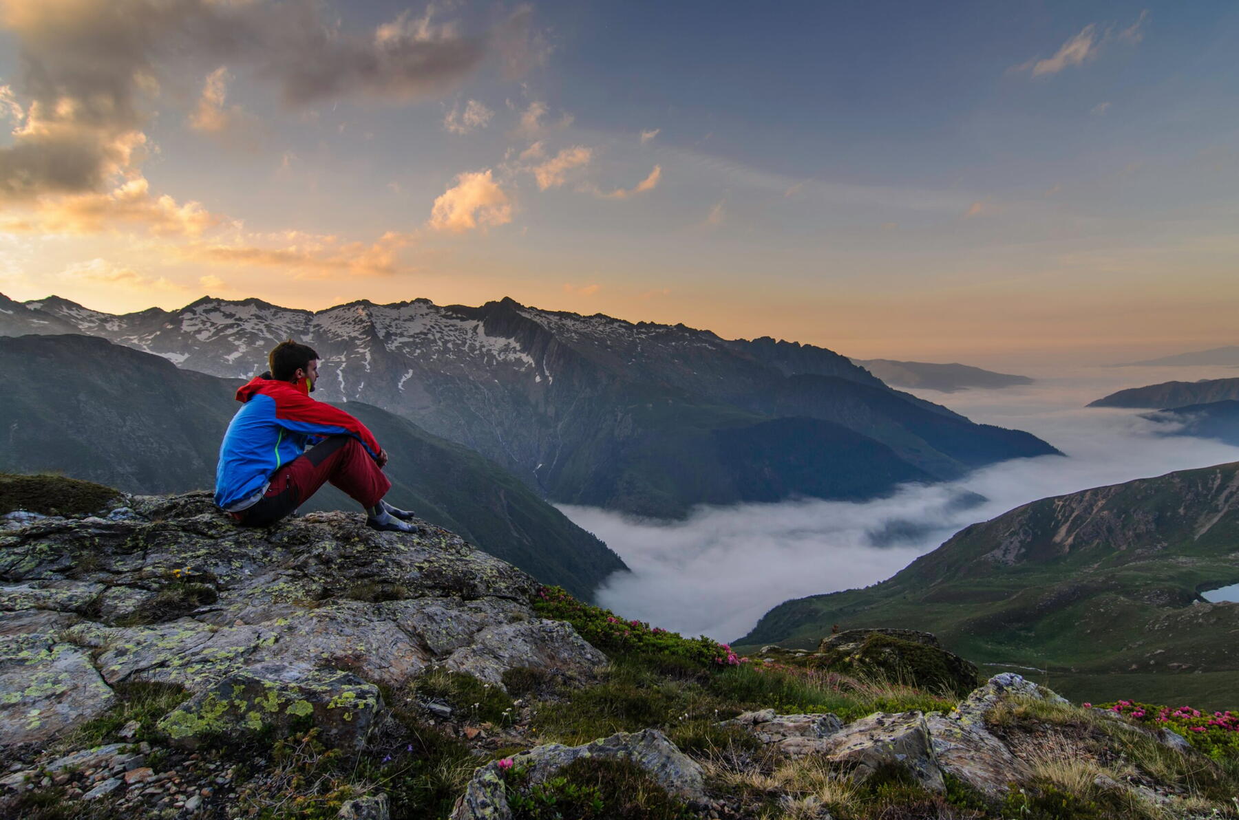 Au petit matin, un voyageur assis face à une mer de nuages dans les Pyrénées