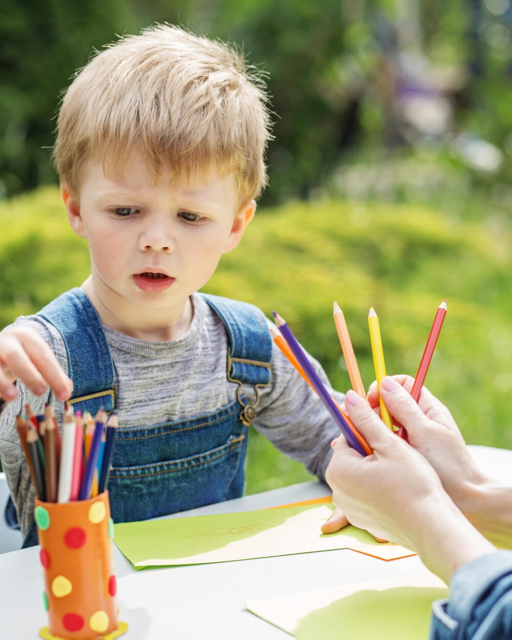 Un enfant choisit ses crayons de couleur lors d’un atelier au jardin